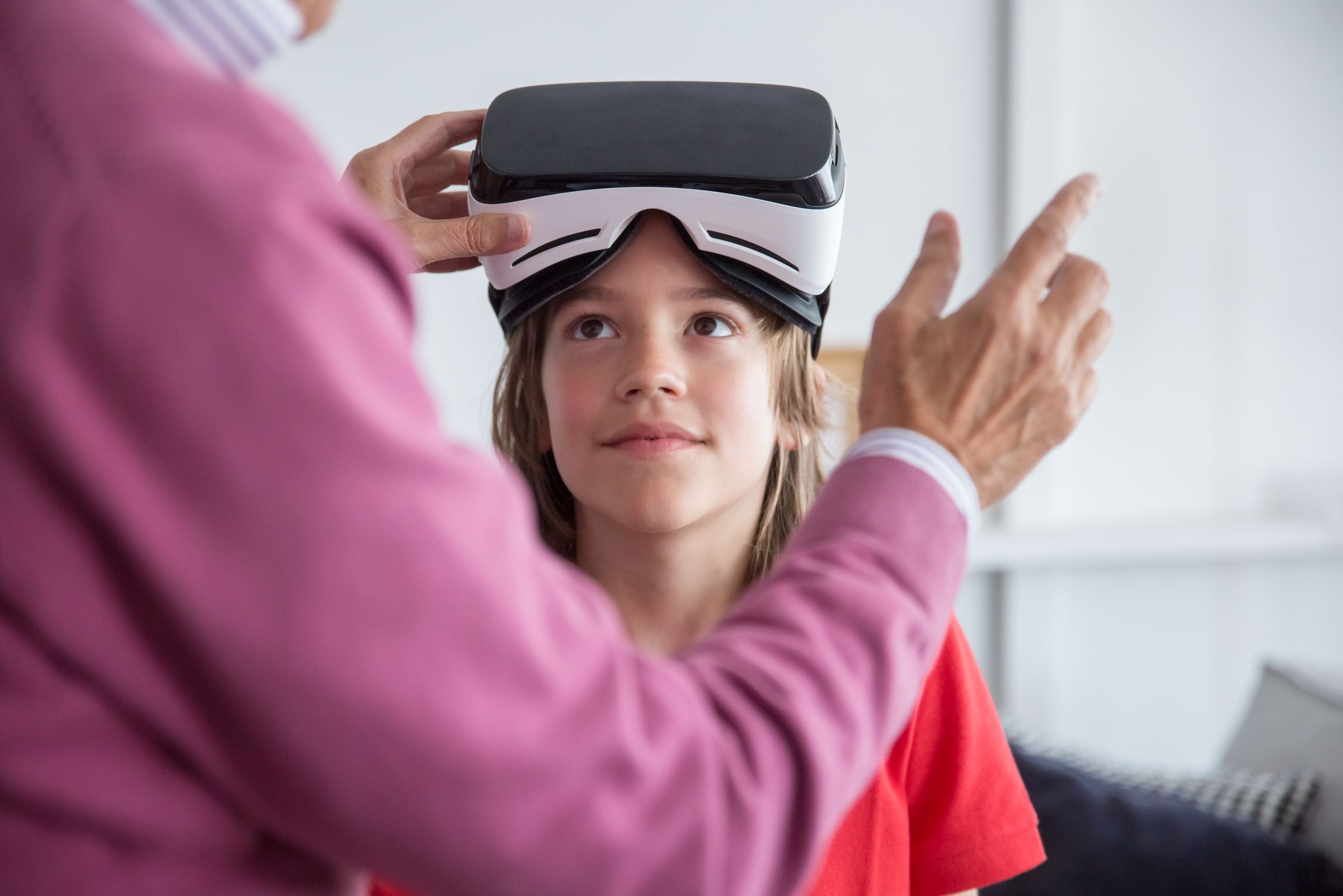 An adult helps a girl put on a VR headset