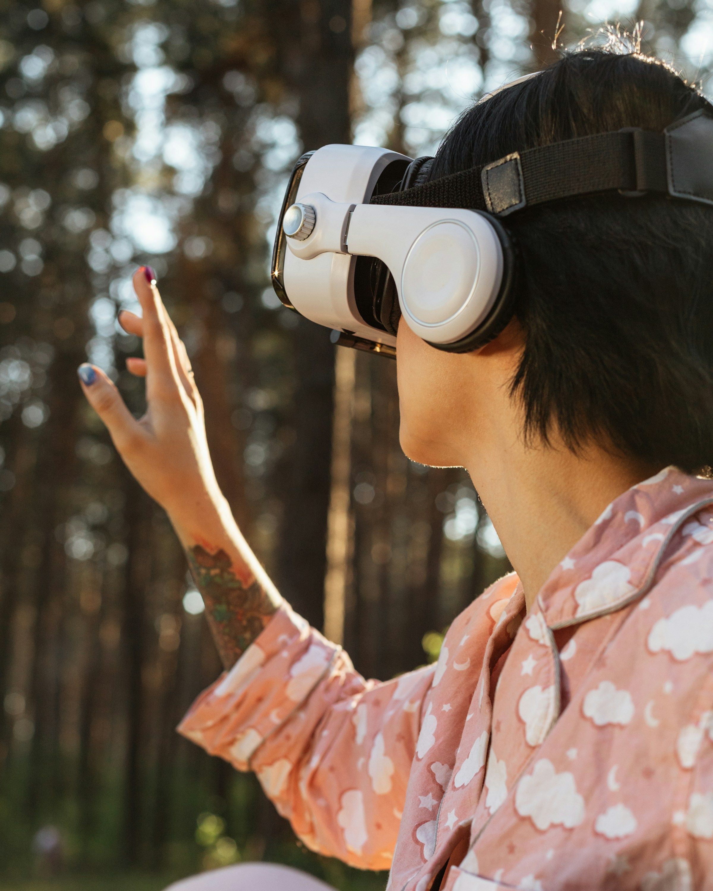 A person in a white VR headset reaches out among pine trees